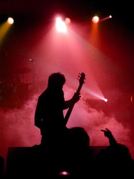 Live Rock Event Stage Production Silhouette of a guitarist performing on stage with red stage lights during a live rock event.