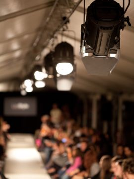 Catwalk Ready with Stage Lights Stage lights shining on a catwalk with a crowd waiting before a show.